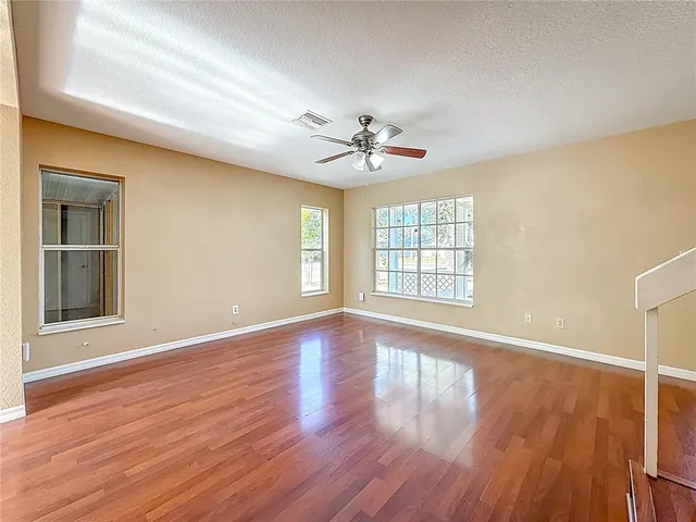 a view of an empty room with window and wooden floor