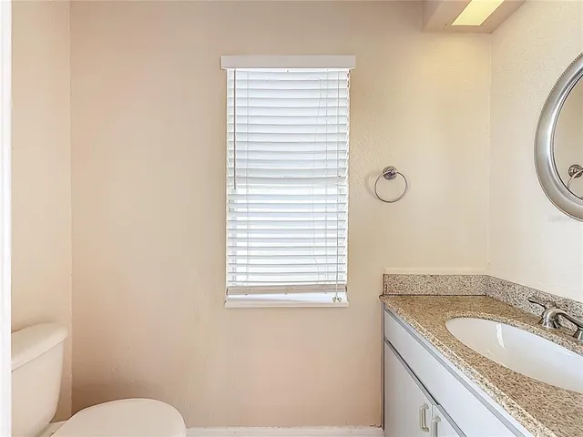 a bathroom with a granite countertop toilet a sink and a mirror