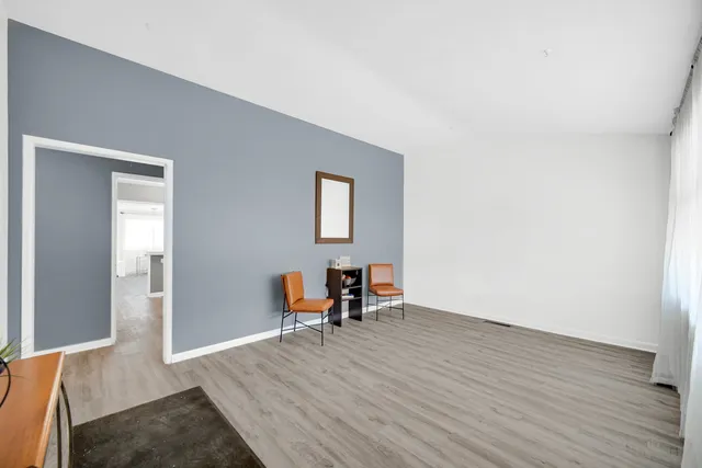 a view of a livingroom with wooden floor and a bench