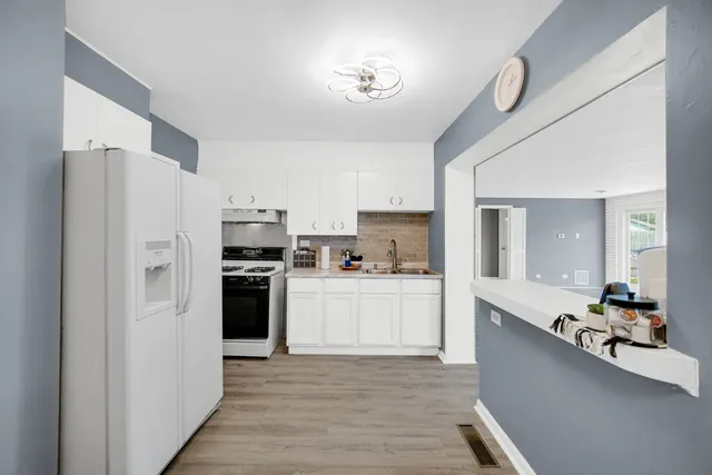 a kitchen with a refrigerator a sink dishwasher a stove and white cabinets with wooden floor