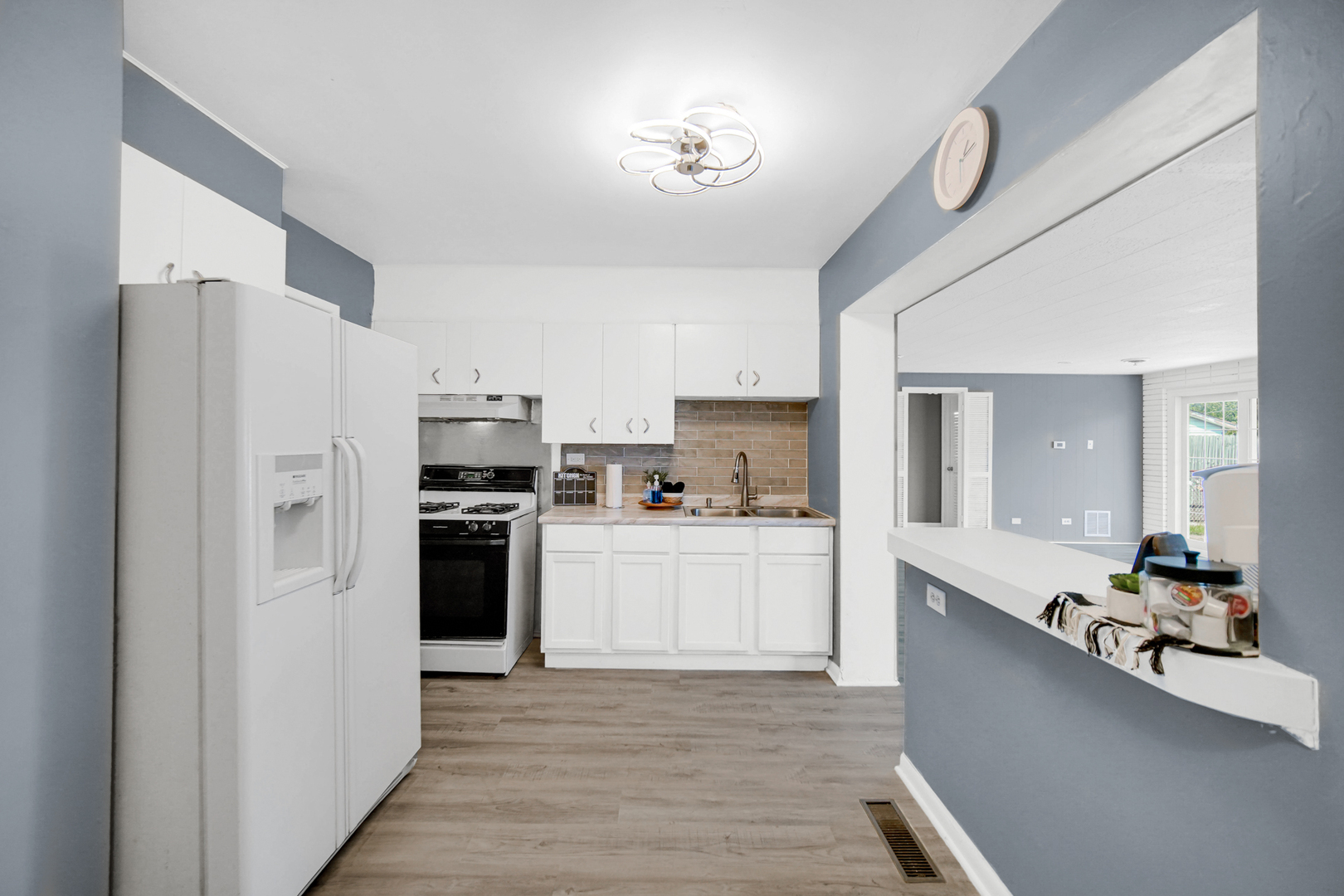1455 Burnham Avenue Calumet City, IL 60409 - Photo 6 of 20 a kitchen with a refrigerator a sink dishwasher a stove and white cabinets with wooden floor