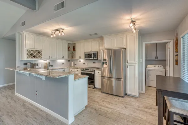 a kitchen with stainless steel appliances granite countertop a sink stove refrigerator and cabinets