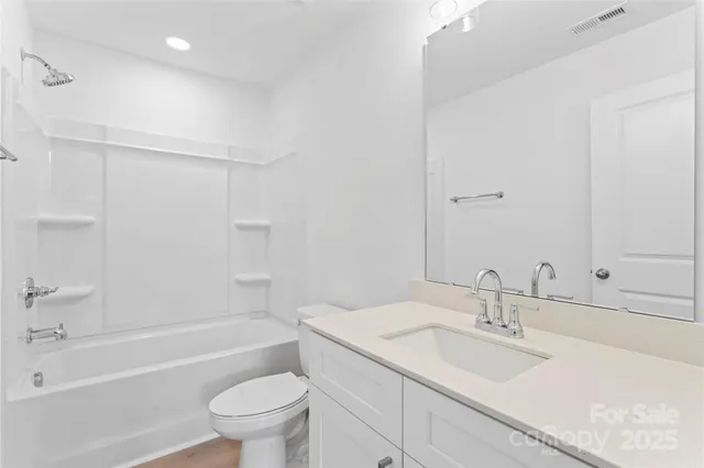 a bathroom with a sink toilet vanity granite tub and shower