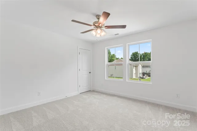 an empty room with windows and ceiling fan