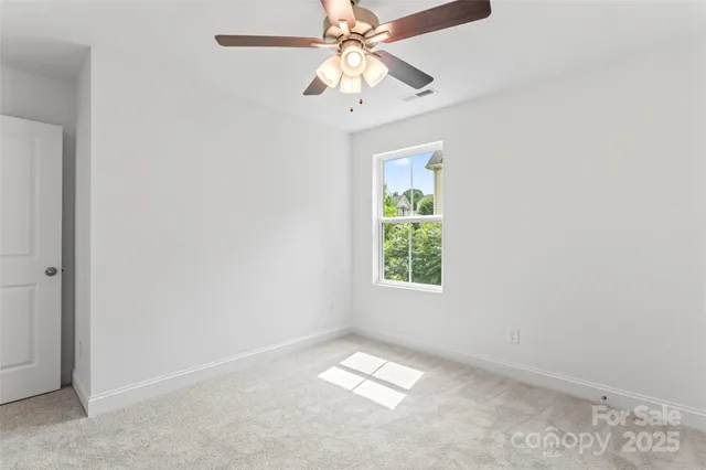 an empty room with a chandelier fan and windows