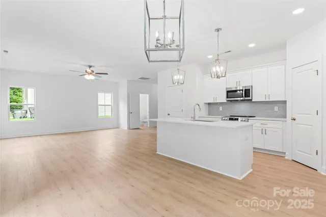 a view of kitchen with kitchen island white cabinets and stainless steel appliances