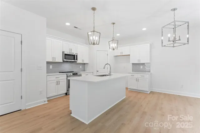 a large kitchen with kitchen island granite countertop a sink a counter space stainless steel appliances and cabinets