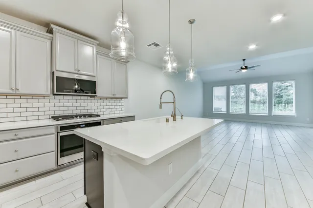 a large kitchen with kitchen island a stove a sink dishwasher and a microwave oven with white cabinets