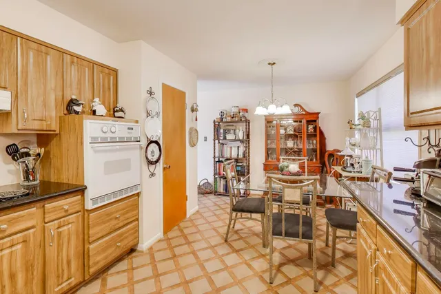 a kitchen with stainless steel appliances kitchen island granite countertop a refrigerator oven a sink dishwasher and white cabinets with wooden floor