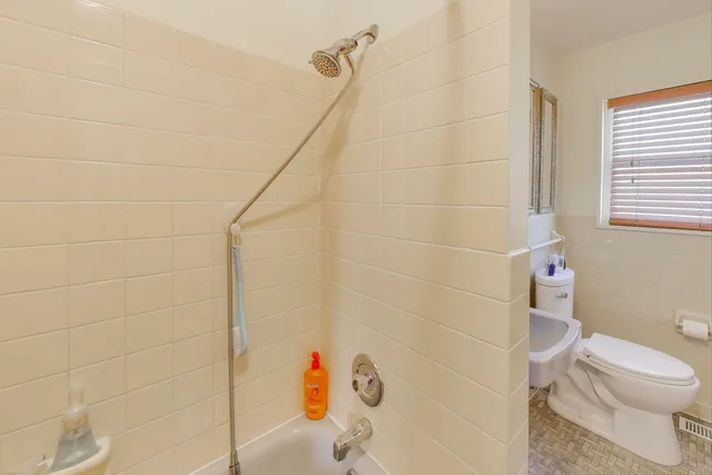 a white toilet sitting next to a bath tub and a shower