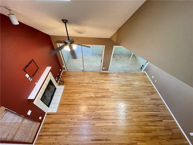 a view of an empty room with wooden floor and a ceiling fan