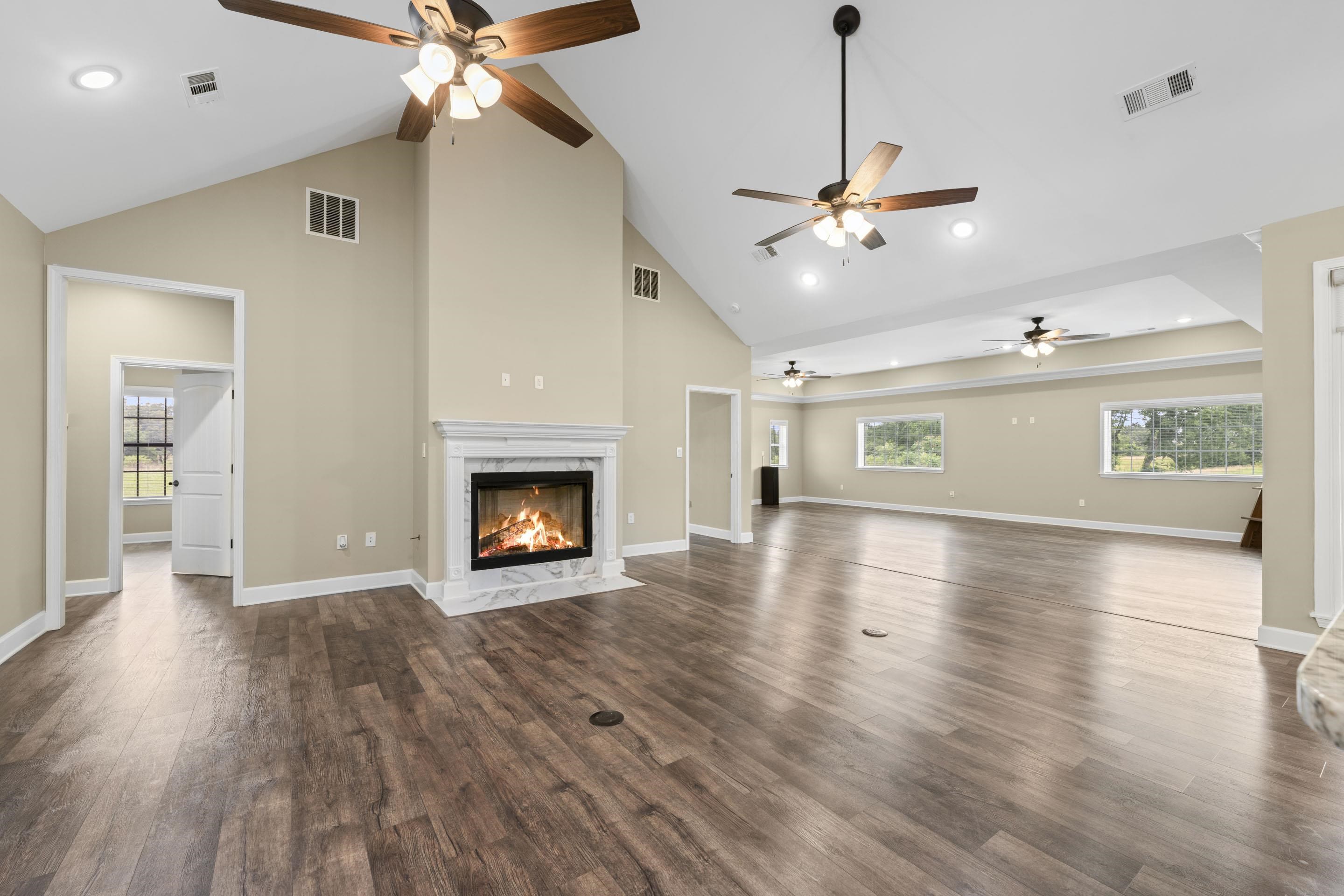 2295 Tomlin Road Somerville, TN 38068 - Photo 6 of 38 Unfurnished living room featuring ceiling fan, a fireplace, dark wood-style flooring, high vaulted ceiling, and recessed lighting