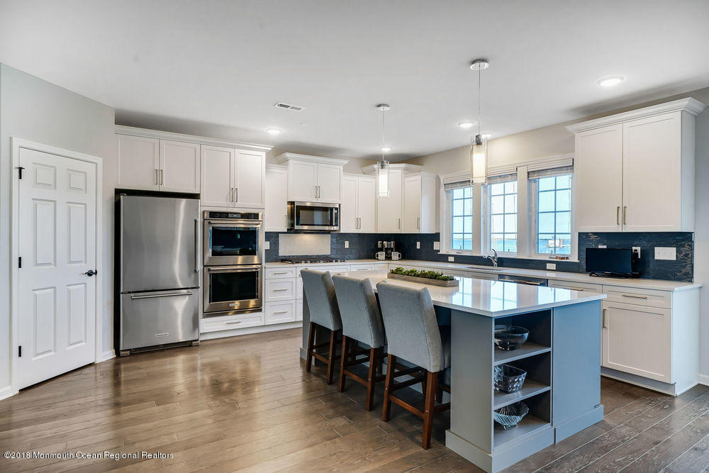 11 Lighthouse Point Road, Unit 601 Highlands, NJ 07732 - Photo 21 of 79 a large kitchen with stainless steel appliances kitchen island granite countertop a stove a refrigerator a sink a stove and white cabinets with wooden floor