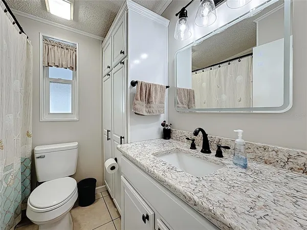 a bathroom with a granite countertop sink a toilet and a shower