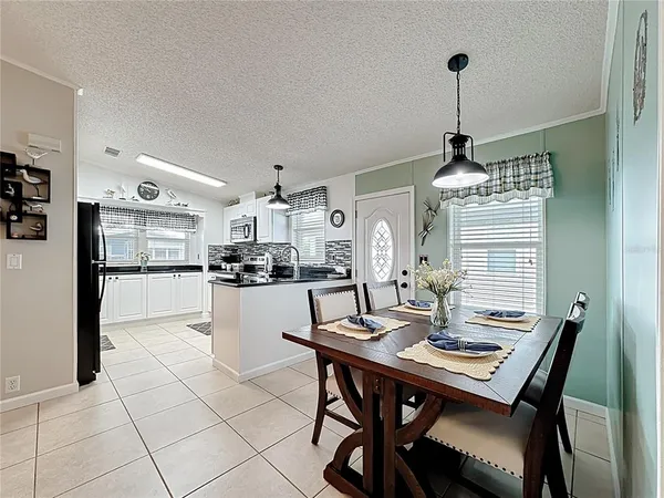 a kitchen with stainless steel appliances kitchen island granite countertop a dining table chairs and a refrigerator