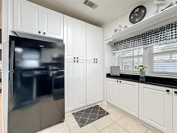 a kitchen with granite countertop a sink a refrigerator and cabinets