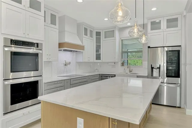 a large kitchen with granite countertop a stove a sink dishwasher and a refrigerator with wooden floor