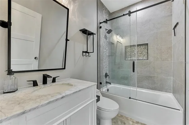 a bathroom with a granite countertop sink toilet and shower