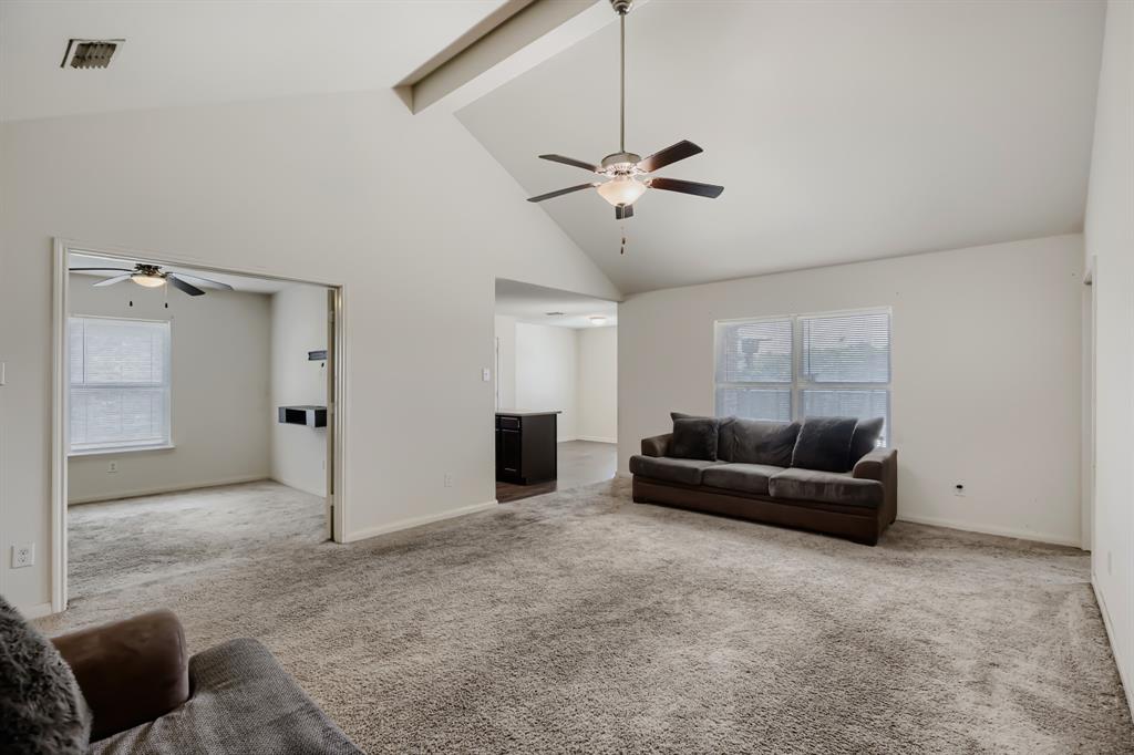 4309 Cat Tail Way Forney, TX 75126 - Photo 10 of 30 Spacious living area featuring a vaulted ceiling with exposed beam, two ceiling fans, and neutral-toned carpeting