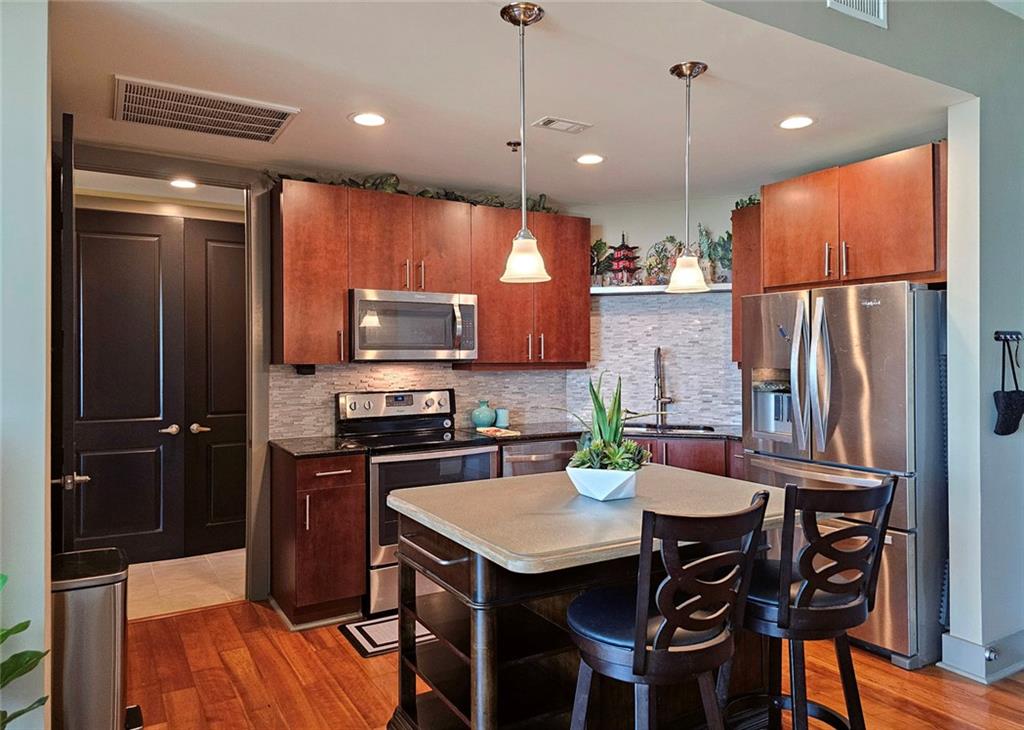 4561 Olde Perimeter Way, Unit 2407 Atlanta, GA 30346 - Photo 6 of 40 a kitchen with stainless steel appliances granite countertop a refrigerator a sink a stove a dining table and chairs