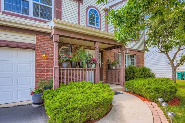 a view of a house with a small yard plants and large tree