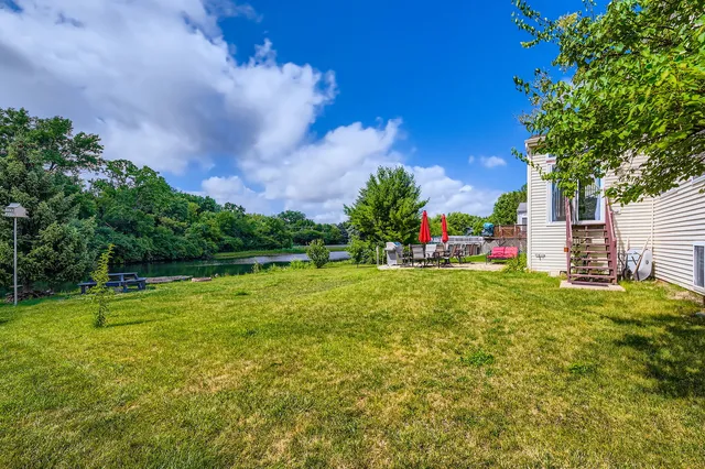 a view of a house with a big yard potted plants and large tree