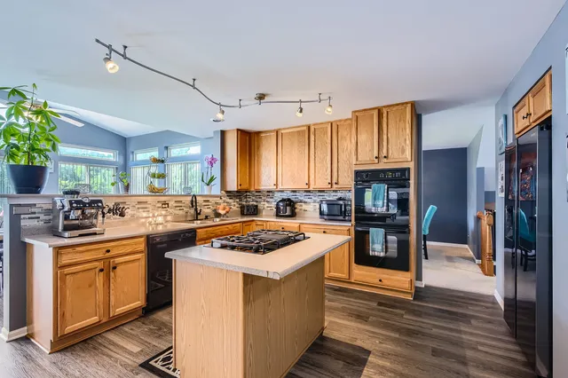 a kitchen with stainless steel appliances granite countertop a stove top oven a sink dishwasher and cabinets with wooden floor