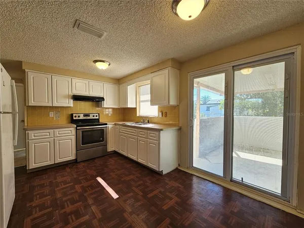 a kitchen with granite countertop a refrigerator and white cabinets