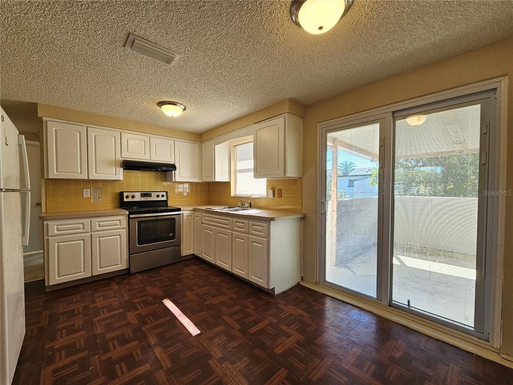 6324 Lomand Avenue New Port Richey, FL 34653 - Photo 4 of 16 a kitchen with granite countertop a refrigerator and white cabinets