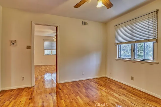 a view of empty room with wooden floor and fan