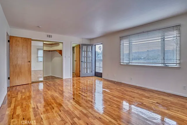 a view of an empty room with wooden floor and a window