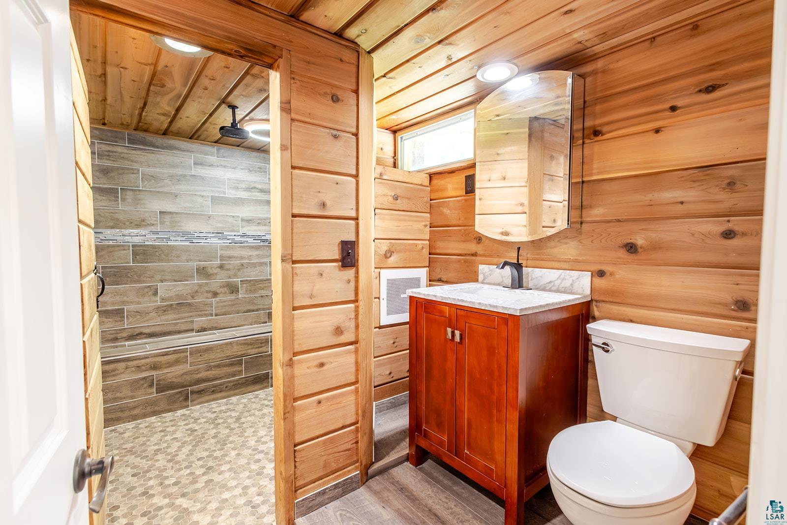 29 Ridge Road Esko, MN 55733 - Photo 30 of 41 Wood-paneled bathroom featuring a cherry wood vanity with a white countertop and rectangular sink