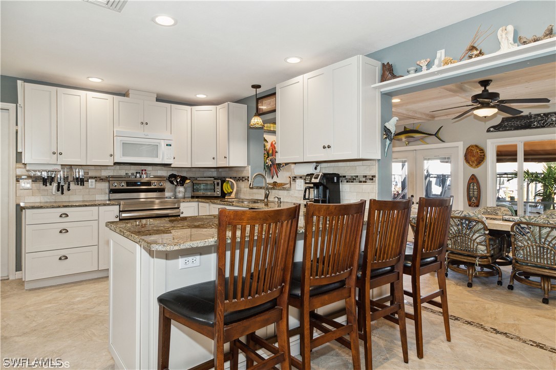 3554 Ruby Avenue St. James City, FL 33956 - Photo 17 of 43 a kitchen with stainless steel appliances granite countertop a table and chairs