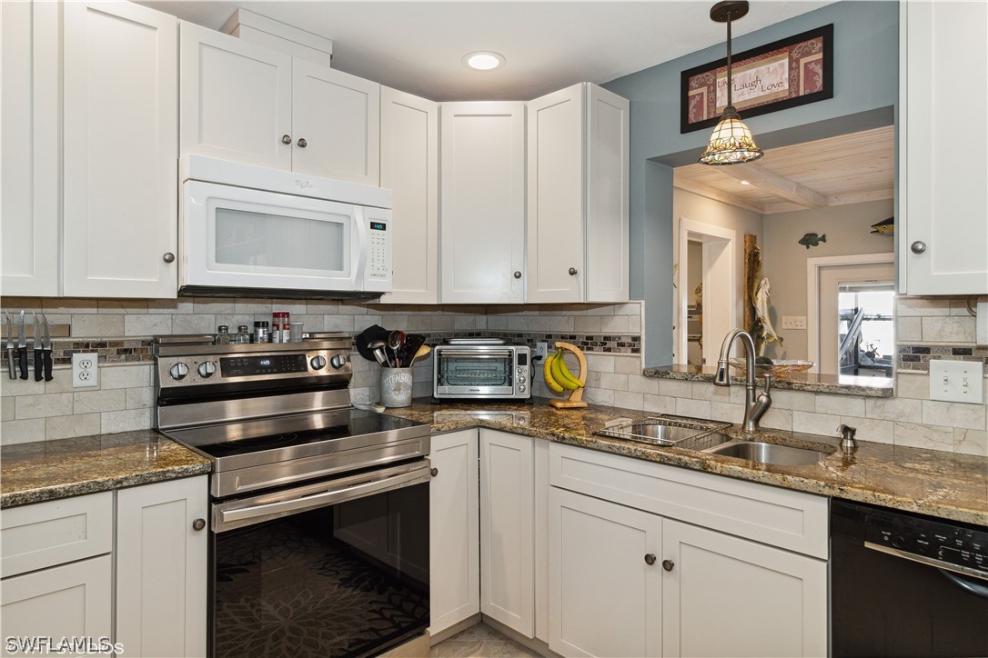 3554 Ruby Avenue St. James City, FL 33956 - Photo 21 of 43 a kitchen with granite countertop white cabinets and stainless steel appliances