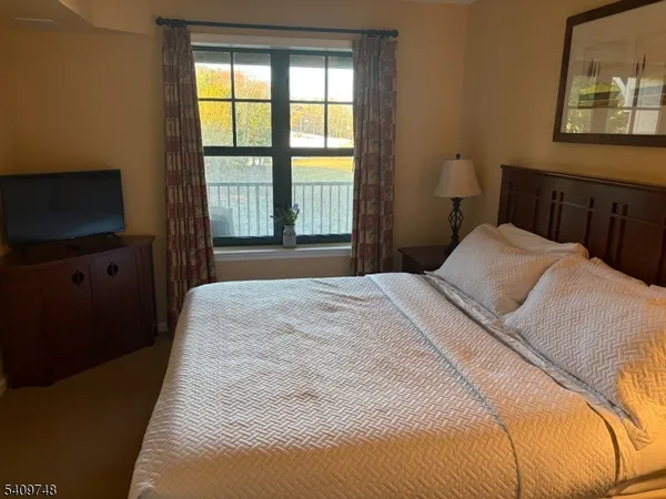 a bedroom with a bed and a flat tv screen on dresser