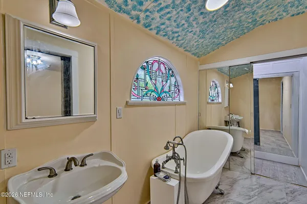 a bathroom with a sink and mirror with bathtub