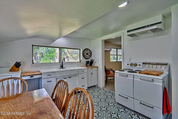 a kitchen with a stove a sink a dining table and chairs