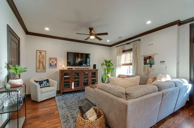 a living room with furniture a ceiling fan and a flat screen tv