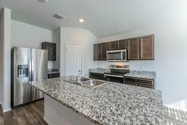 a kitchen with stainless steel appliances granite countertop a refrigerator and a stove top oven