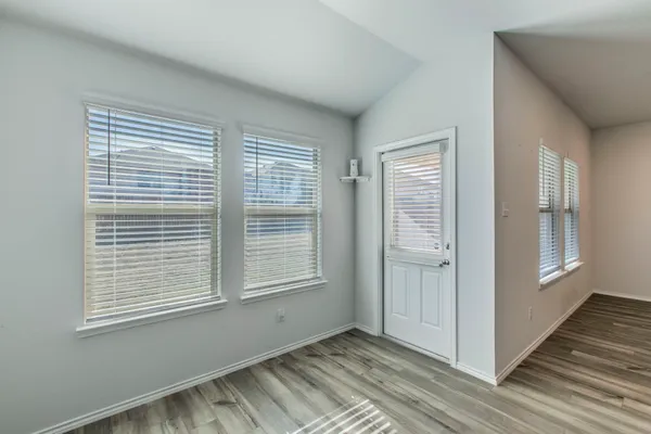 a view of an empty room with wooden floor and a window