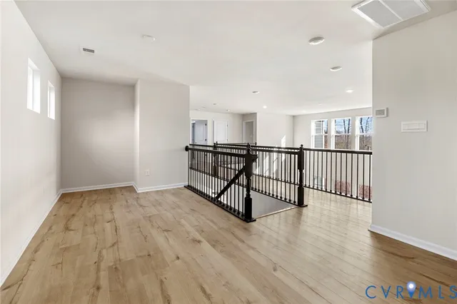 a view of a hallway with wooden floor and windows