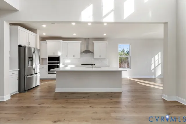 a large kitchen with stainless steel appliances kitchen island a large counter top and a refrigerator