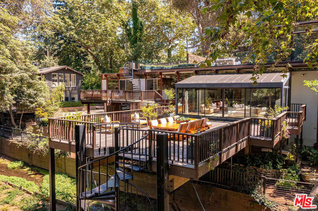 681 Brooktree Road Santa Monica, CA 90402 - Photo 32 of 32 a view of a patio with table and chairs under an umbrella with wooden fence