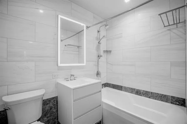 a front view of multi story residential apartment building with entryway yard and wooden fence