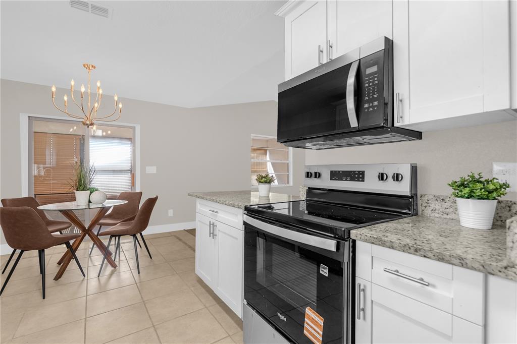 3324 Fox Ridge Drive Winter Haven, FL 33884 - Photo 9 of 28 a kitchen with stainless steel appliances a stove a microwave and white cabinets