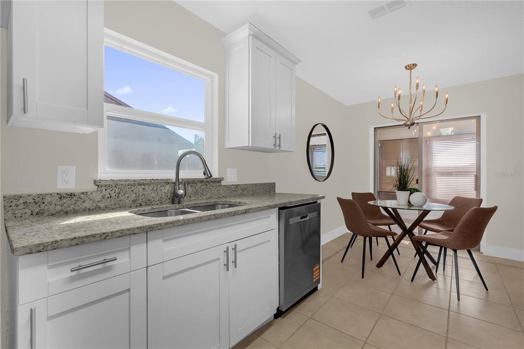 3324 Fox Ridge Drive Winter Haven, FL 33884 - Photo 10 of 28 a hall with kitchen island granite countertop a sink a table and chairs in it