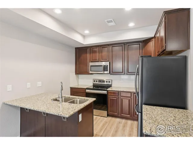 a kitchen with kitchen island granite countertop a sink stove and refrigerator