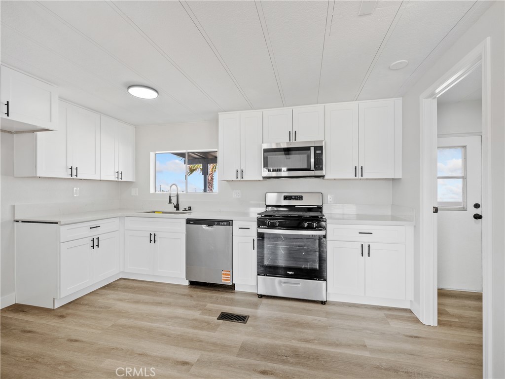 11669 Sahara Road Phelan, CA 92371 - Photo 3 of 34 a kitchen with stainless steel appliances a sink a stove a microwave and cabinets
