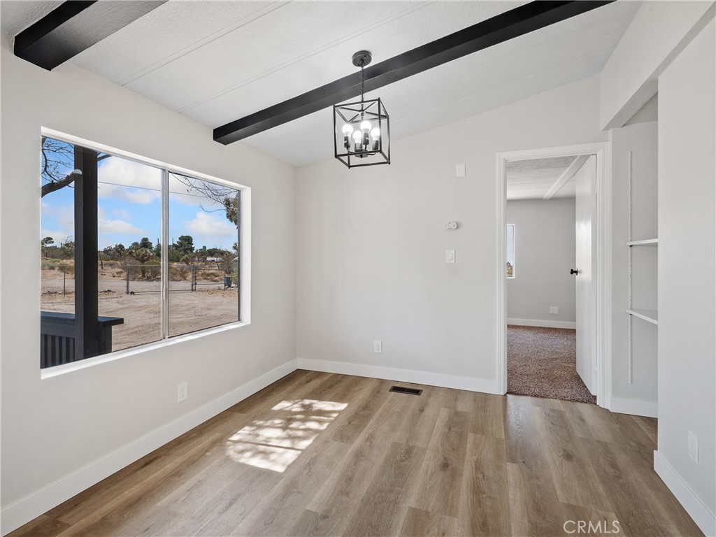 11669 Sahara Road Phelan, CA 92371 - Photo 5 of 34 a view of an empty room with wooden floor and a window