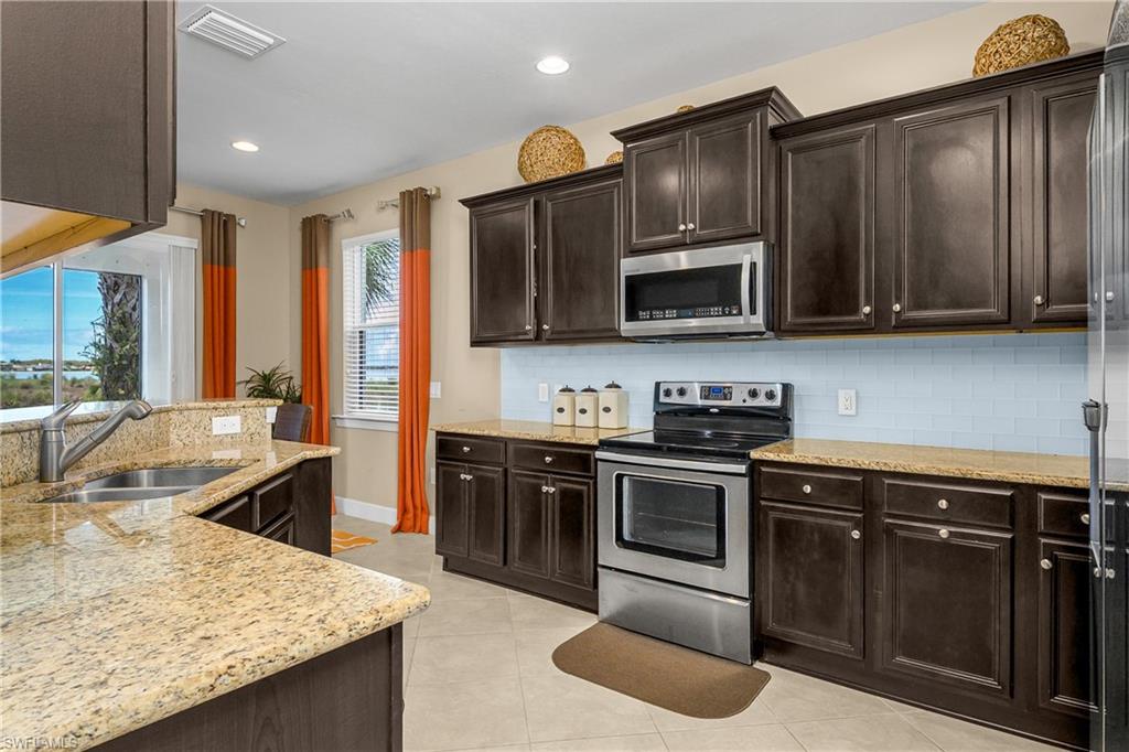 9064 Siesta Bay Drive, Unit 5102 Naples, FL 34120 - Photo 6 of 46 Open and spacious kitchen features granite countertops, stainless steel appliances, tile backsplash, pantry, and stunning views!